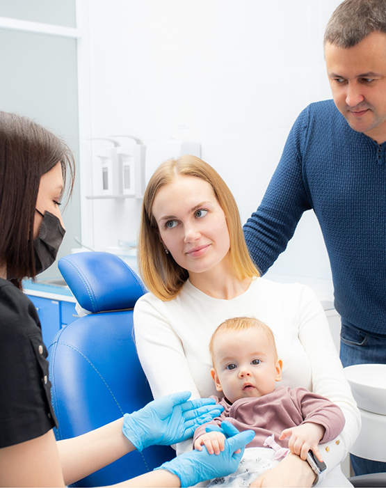 Mother holding baby while sitting in dental chair
