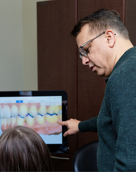 Man with glasses showing render of teeth to dental patient