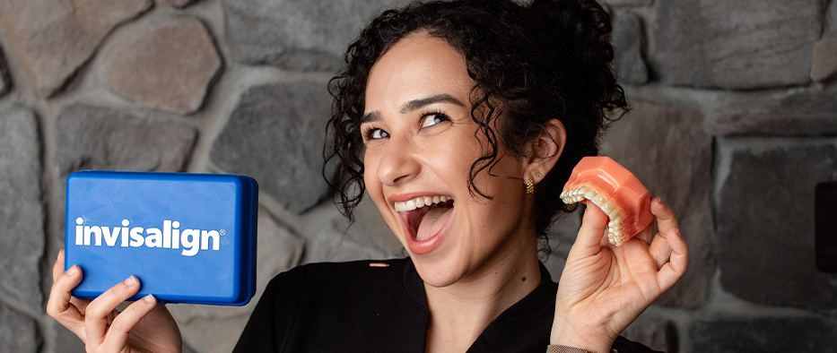 Smiling woman holding dentures and a case that says Invisalign