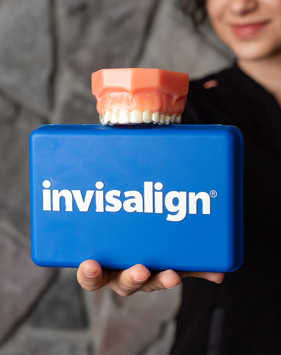 Holding case that says Invisalign with dentures balanced on top