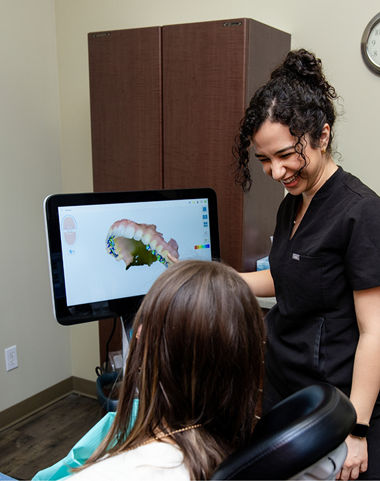 Dr. Hanin Musbah showing patient monitor with a render of an arch of teeth