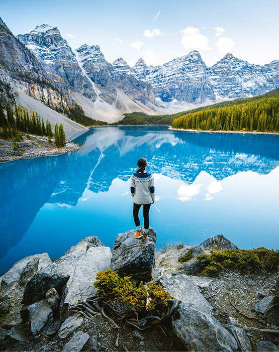 Woman in sweater looking at a scenic lake in the mountains