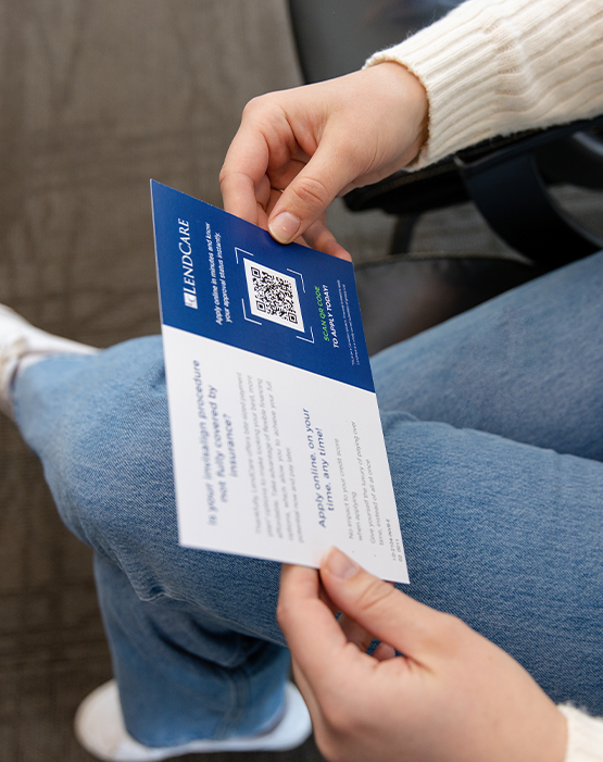 Person in sweater holding card for LendCare
