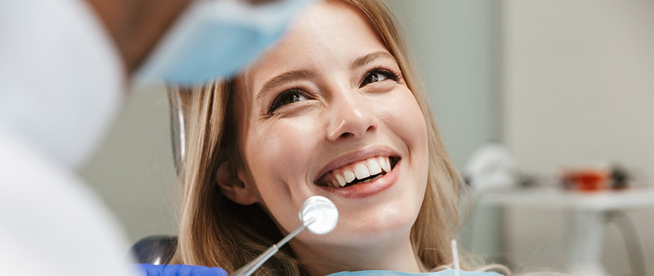 Woman in the dental chair smiling up at her dentist